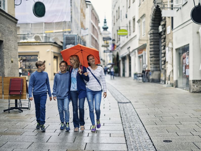 Eine Mutter läuft mit ihren Kindern im Regen durch Salzburg, Österreich. © Imgorthand/E+ via Getty Images
