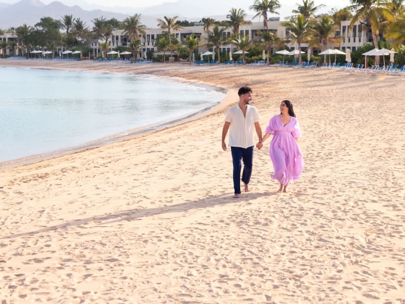 Ein Paar läuft Hand in Hand über einen Strand in Ras Al Khaimah