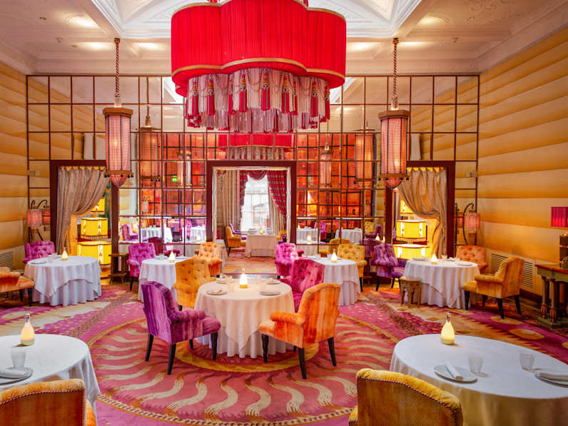 Ein Raum mit runden Tischen, Plüschsesseln und Teppichen.