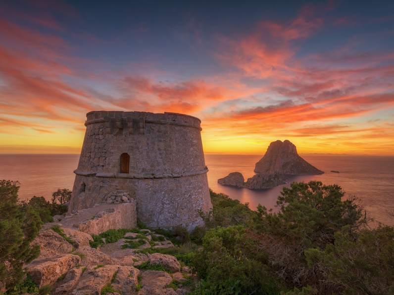 Ein historischer Turm bei Dämmerung mit einer Insel im Hintergrund