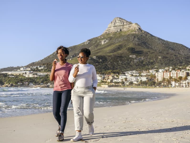 Zwei junge Frauen essen gemeinsam am Strand Eis.