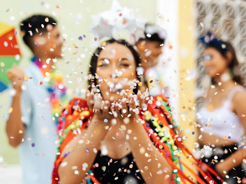 Frau feiert Karneval mit Freunden und Konfetti.
