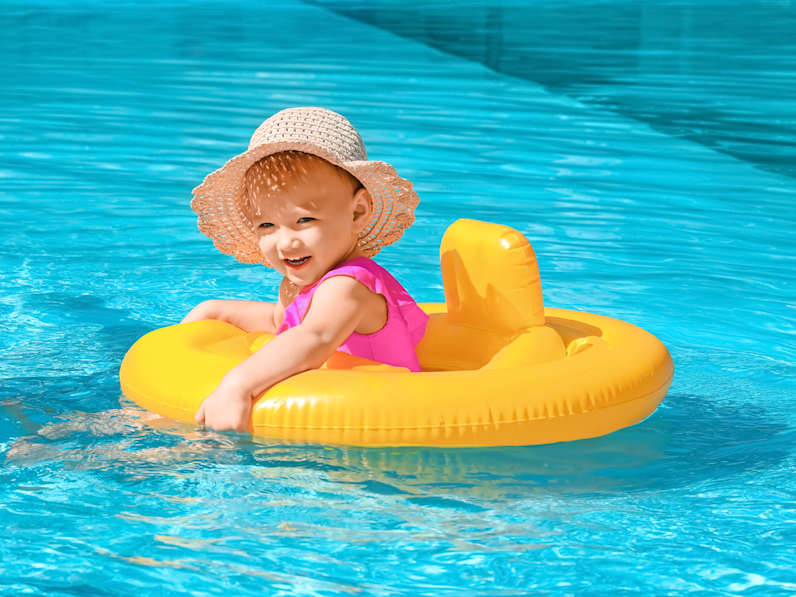 Kleines Mädchen in Pool in einem gelben Schwimmring.