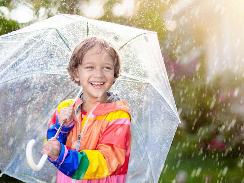 Lachendes Kind unter einem Regenschirm.