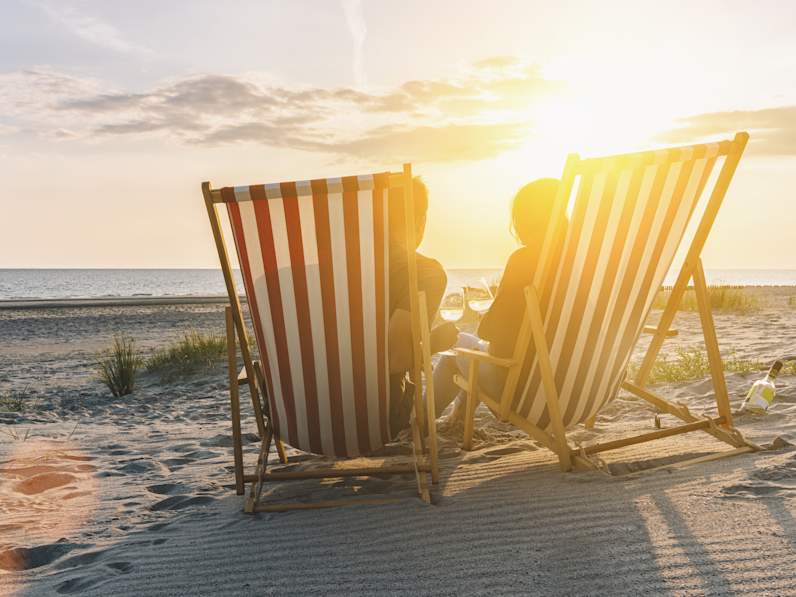 Zwei Personen in Liegestühlen im Sonnenuntergang am Ostseestrand