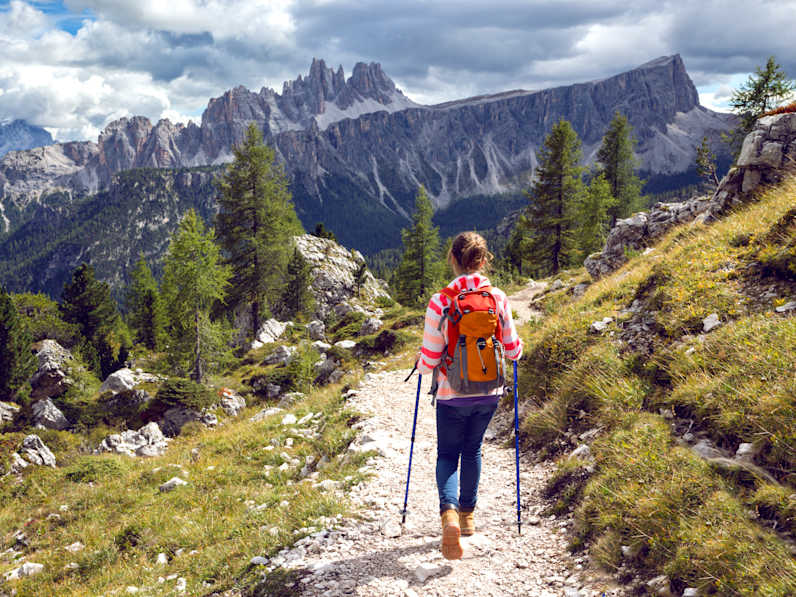 Eine Frau wandert auf einem schmalen Wanderweg vor einer spektakulären Bergkulisse in den Dolomiten in Südtirol, Italien ©shutterstock_1140667871