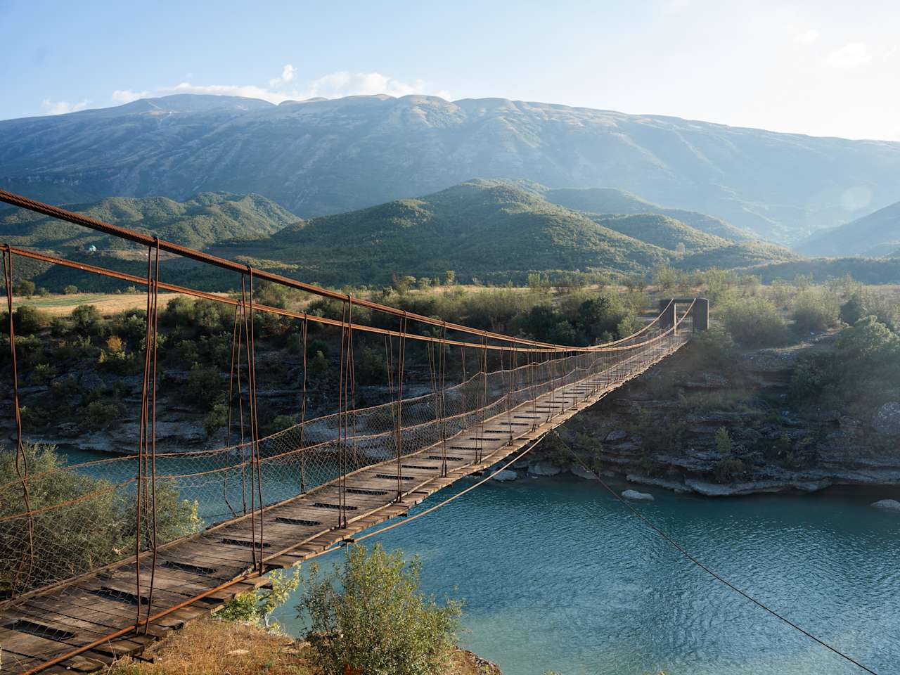 Eine hölzerne Hängebrücke verbindet zwei Landstücke miteinander