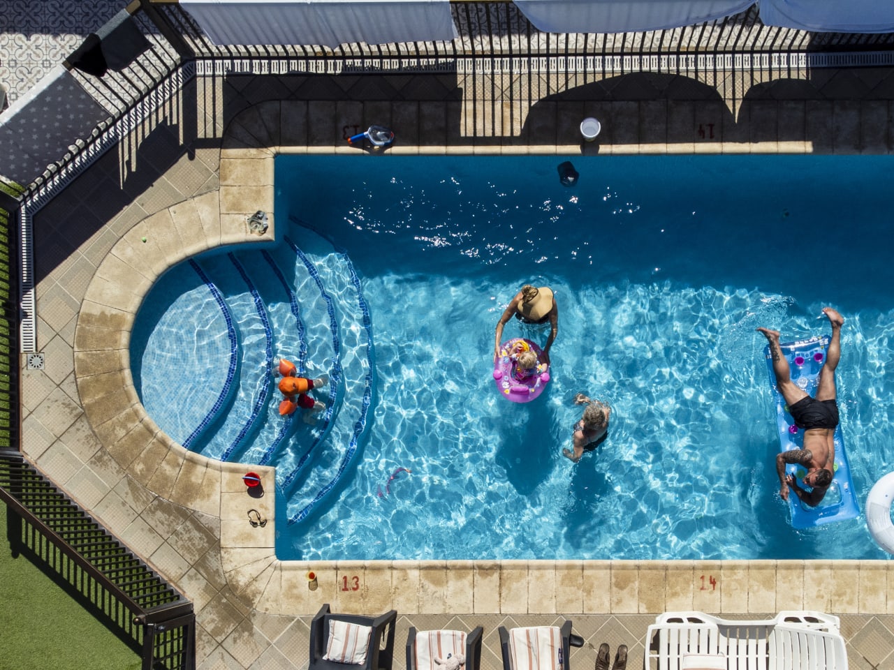 Aufnahme einer altersgemischten Familie in und um ein Schwimmbad auf Teneriffa © iStock.com/SolStock