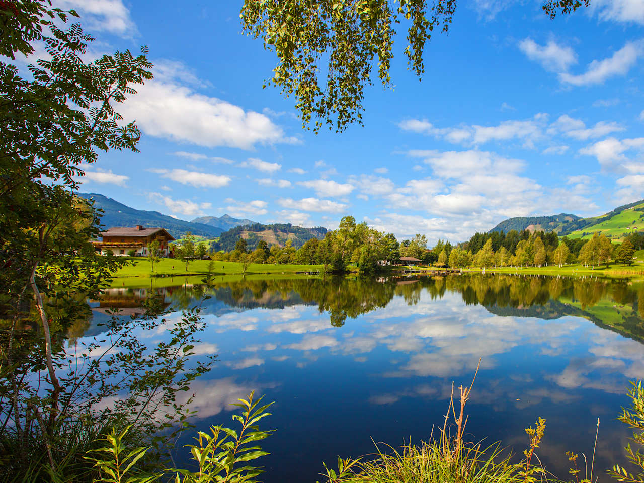 Ausblick auf den Böndlsee in Goldegg im Pongau umgeben von Wiesen, Wäldern und Bergen