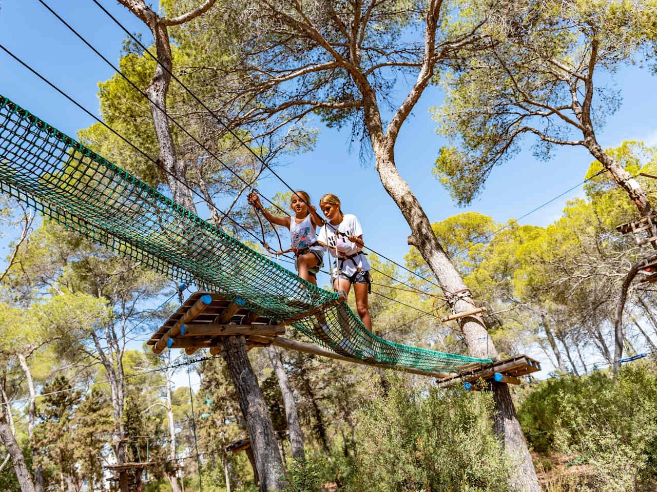Zwei Kindern klettern in einem Kletterwald auf Ibiza