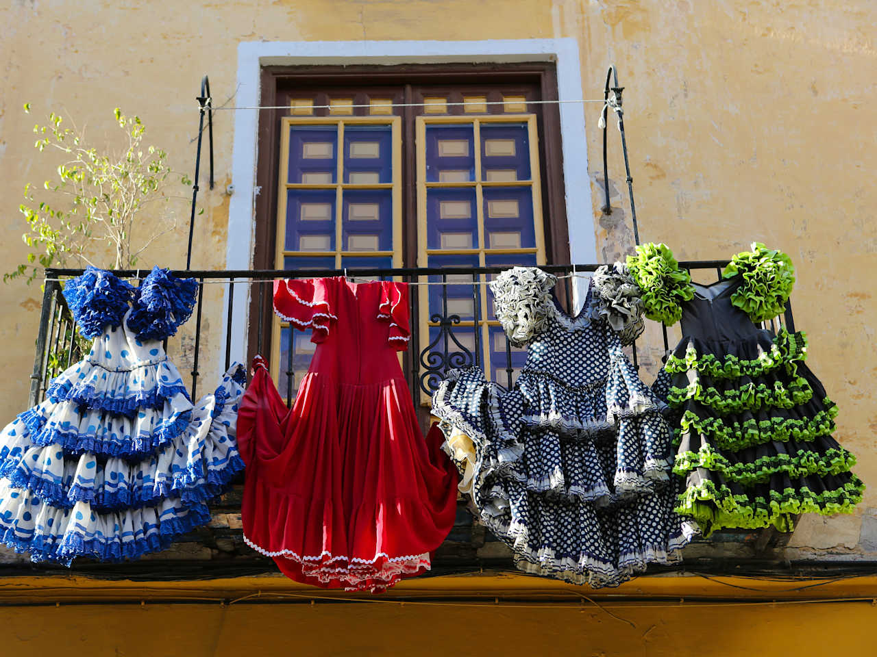 Vier Flamencokleider hängen am Geländer eines Balkons
