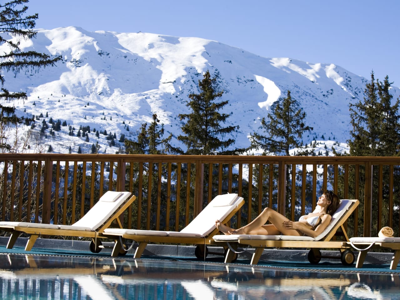 Frau entspannt auf Liegestuhl am Außenpool eines Wellnesshotels in den Bergen ©iStock.com/plprod