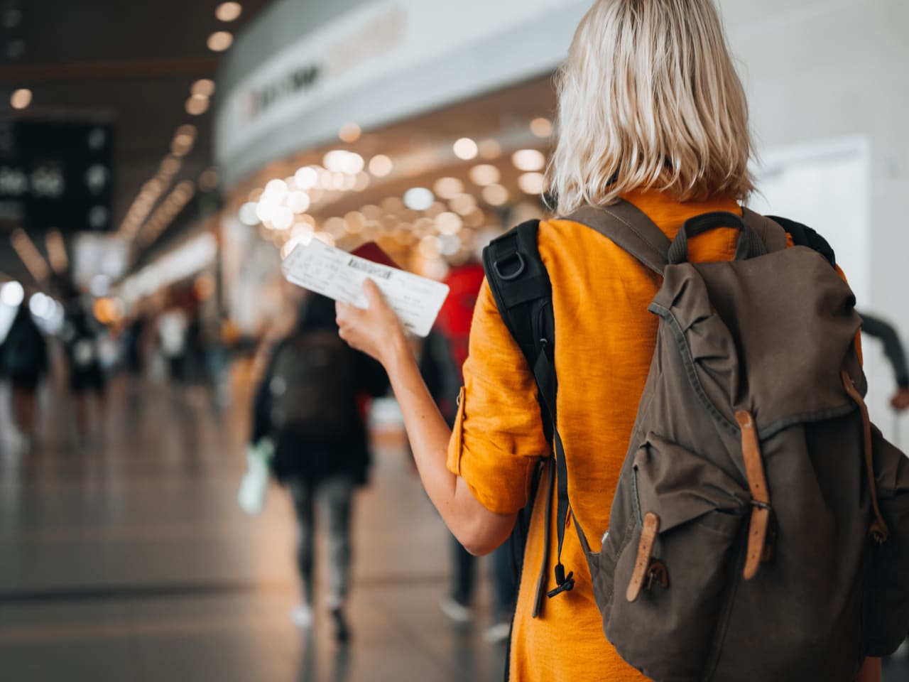 Frau mit Flugticket und Rucksack am Flughafen © iStock.com/Pyrosky