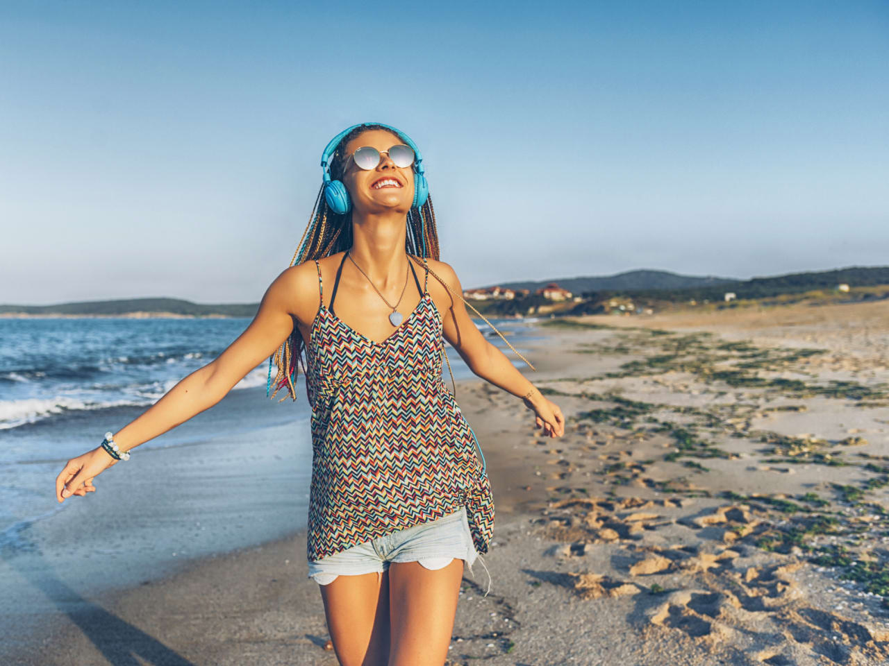 Fröhliche junge Frau hört Musik mit Kopfhörern am Strand © iStock.com/Vladimir Vladimirov