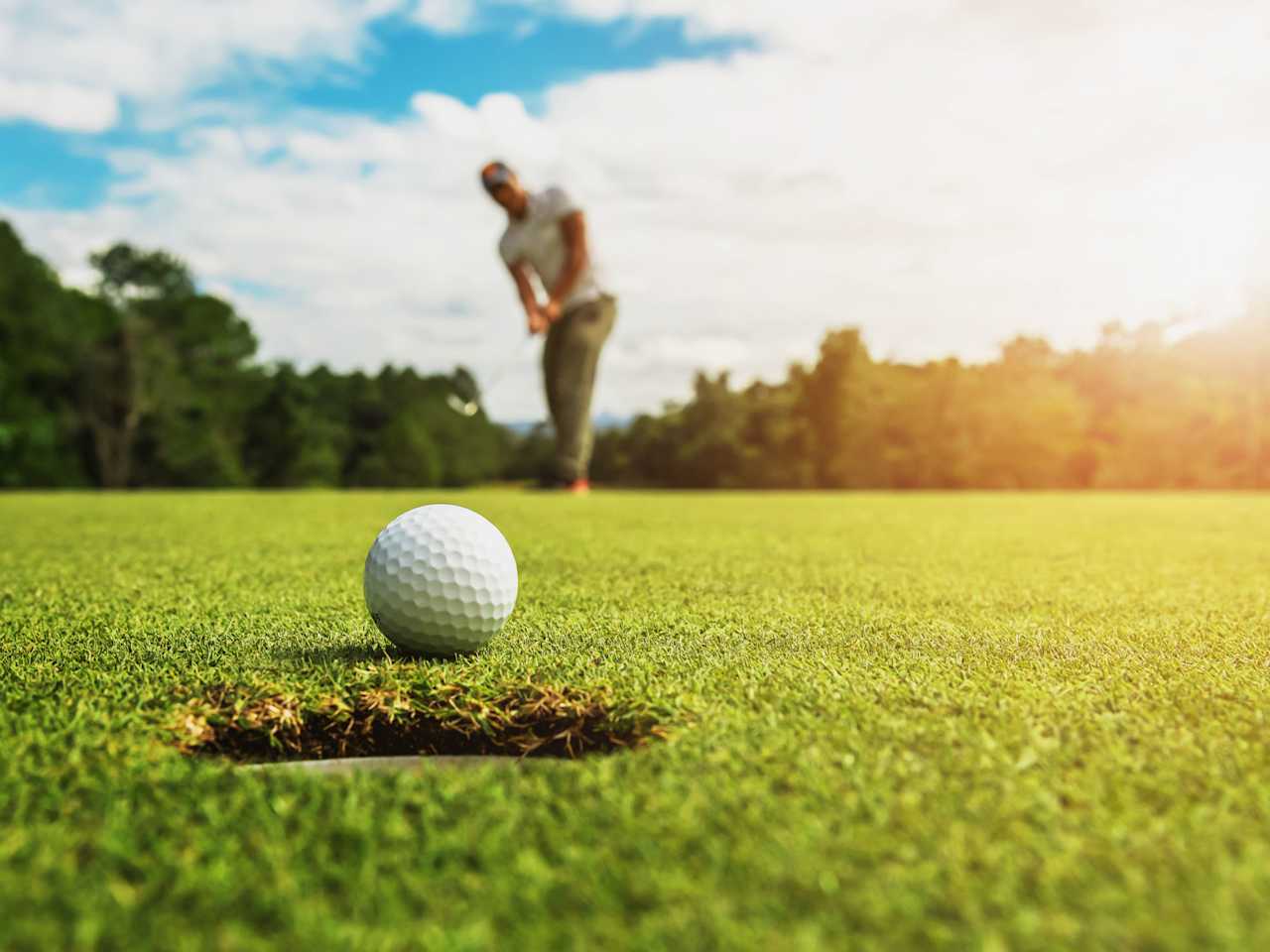 Golfer beim Putt – der Ball kurz vor dem Loch