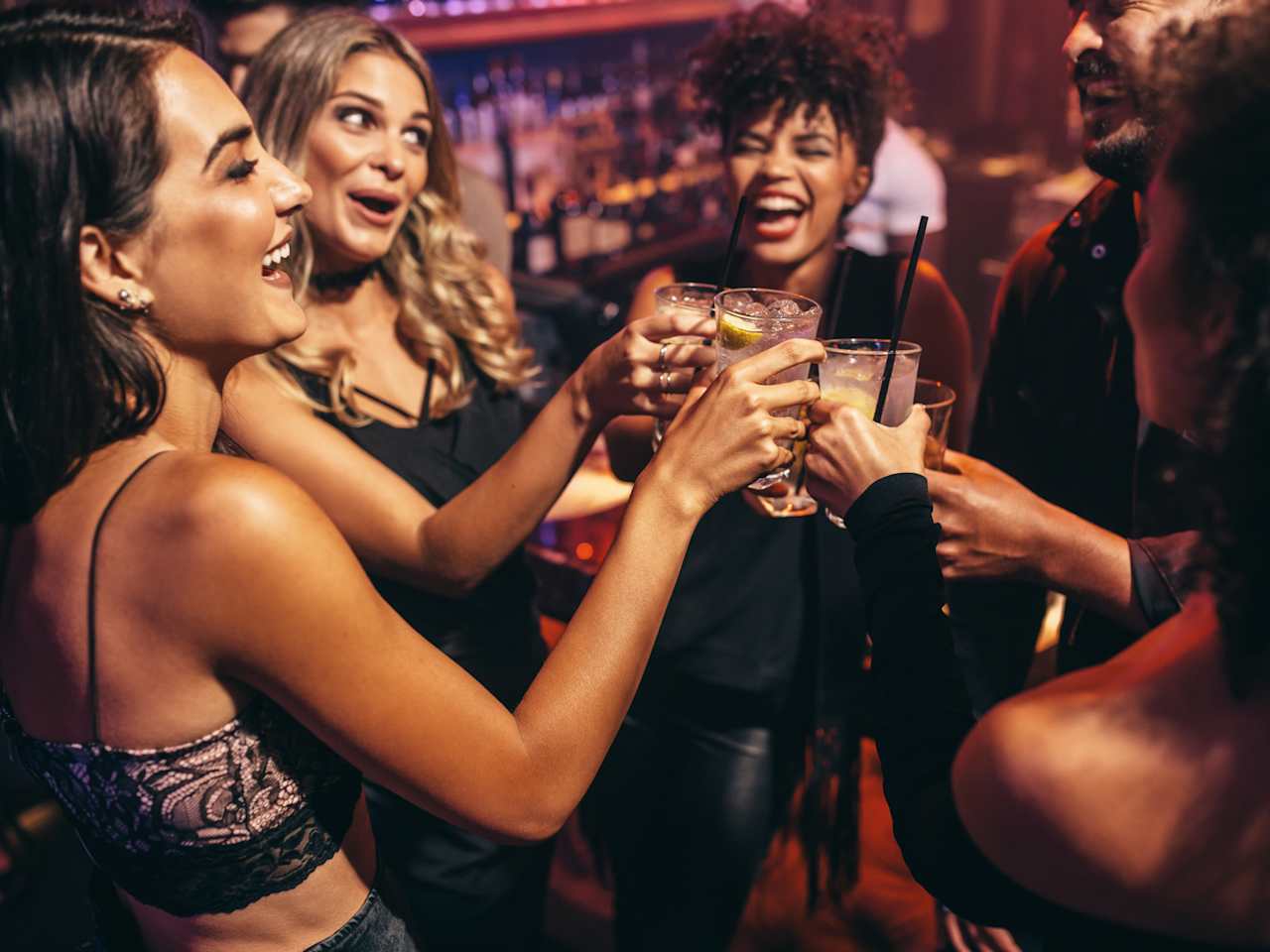 Eine Gruppe von Freunden stößt mit Cocktails in einem Nachtclub an. © jacoblund/iStock / Getty Images Plus via Getty Images