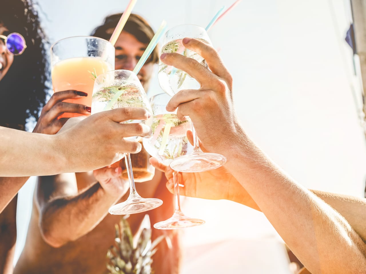 Gruppe von Freunden stoßen mit tropischen Cocktails an © iStock.com/DisobeyArt