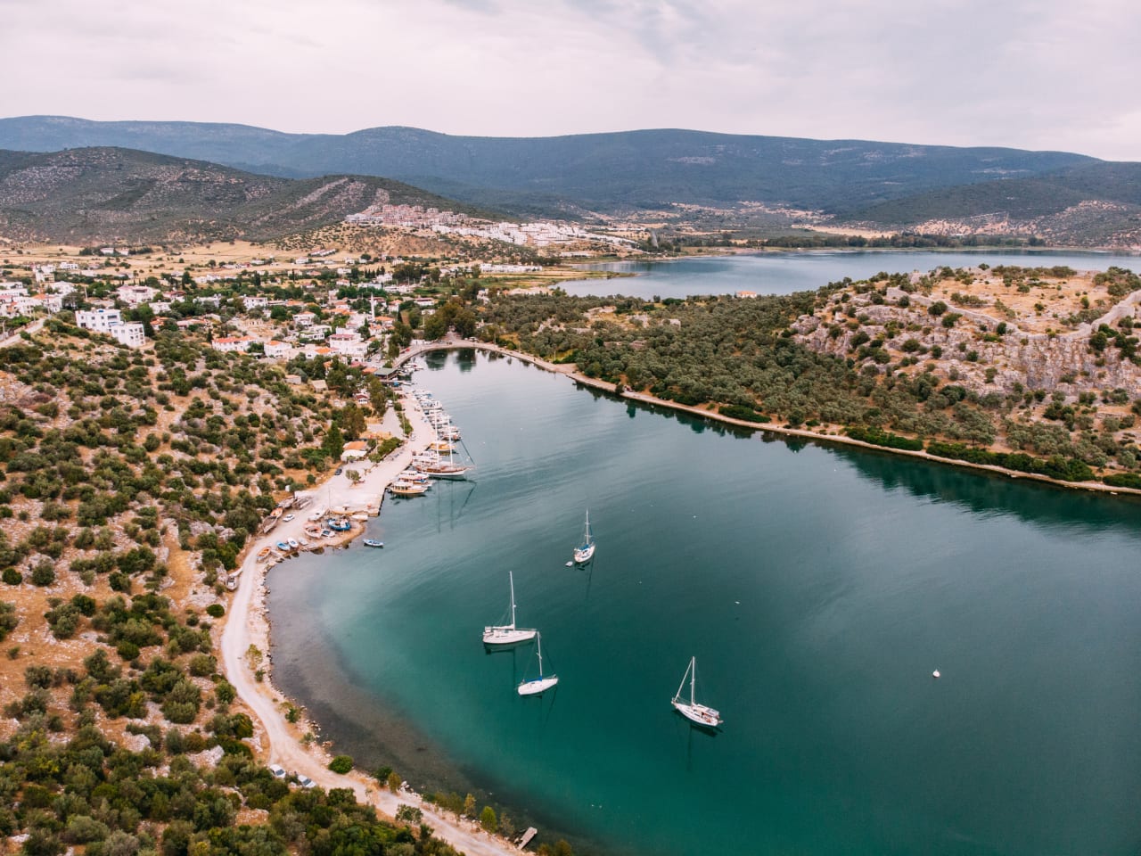 Luftaufnahme einer kleinen Küstenstadt und Segelbooten im Meer © iStock.com/AegeanBlue