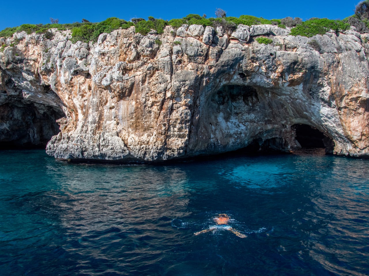 Person taucht zu einer Höhle an der Küste Mallorcas im Mittelmeer © iStock.com/Thomas Bernd
