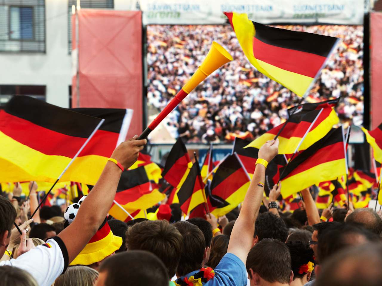 Fans mit Deutschlandflaggen vor einem großen Bildschirm