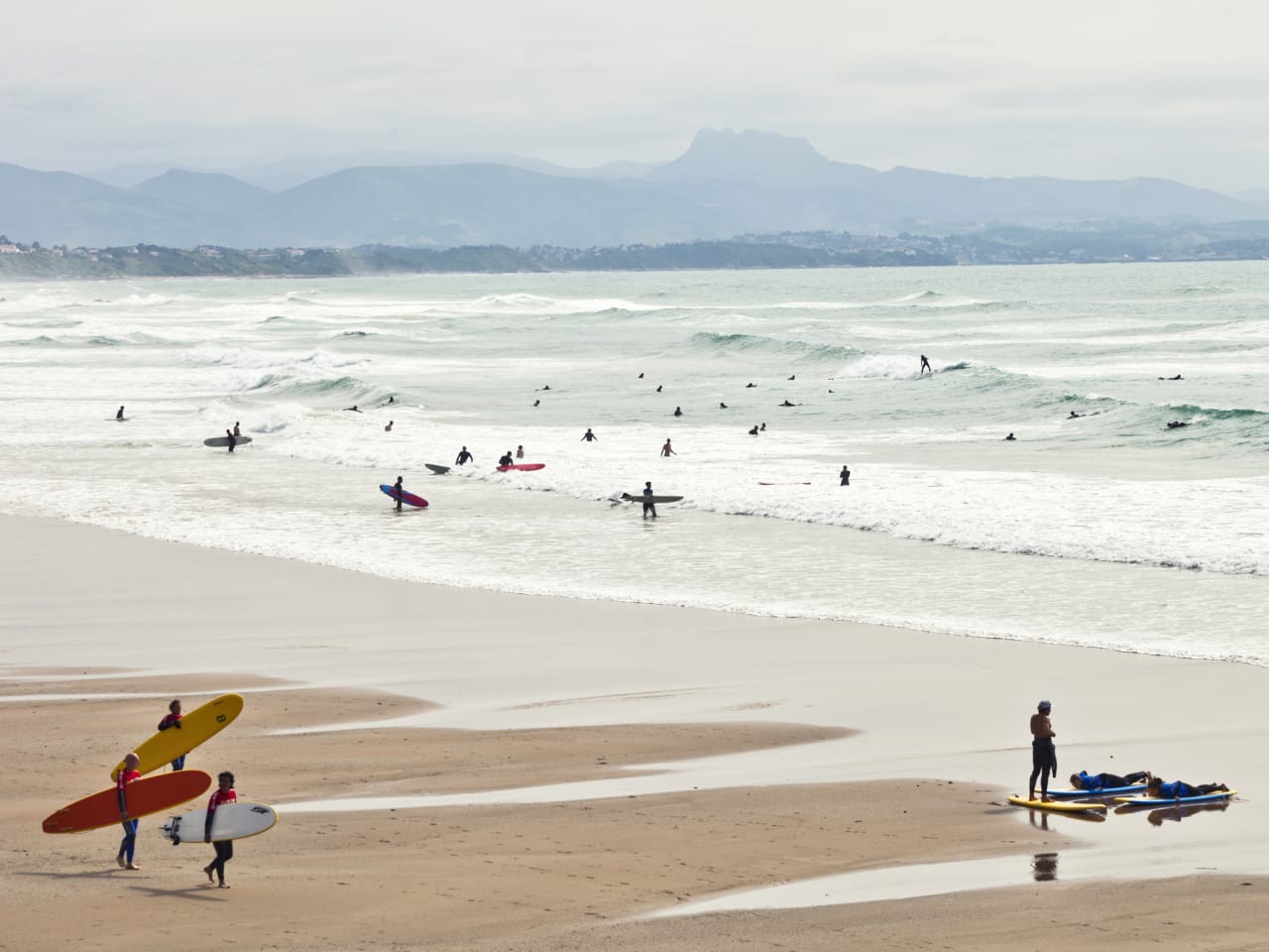 Surfer laufen am Strand und reiten die Wellen © iStock.com/peeterv