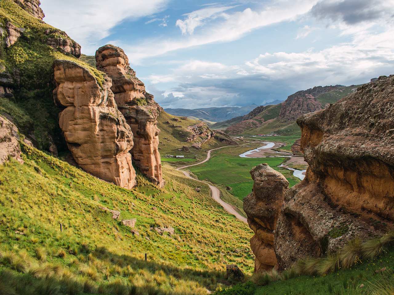 Blick aus Felsen an Berghang auf Tal mit Pfad und Bach zwischen steinigem Tinajani Gebirge in Perus Anden.
