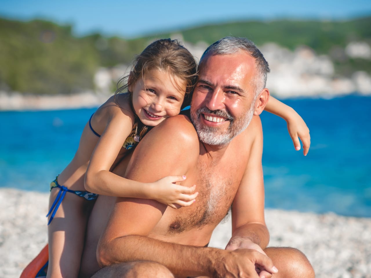 Vater mit seiner Tochter beim Strandurlaub ©CasarsaGuru/iStock