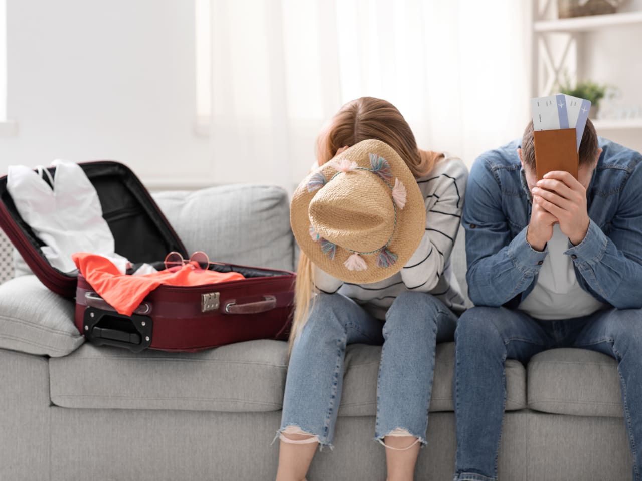 Paar sitzt traurig zu Hause in der Nähe von gepackten Koffer für den Urlaub ©iStock.com/Prostock-Studio