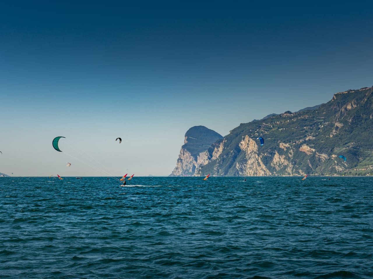Windsurfer und Kitesurfer am Gardasee in Italien © iStock.com/no_limit_pictures