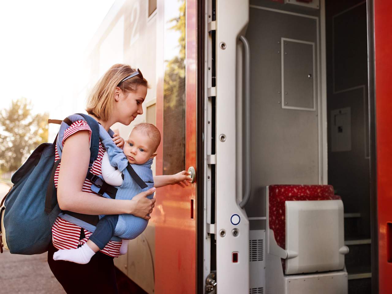 Frau mit Baby in der Trage steigt in einen Zug