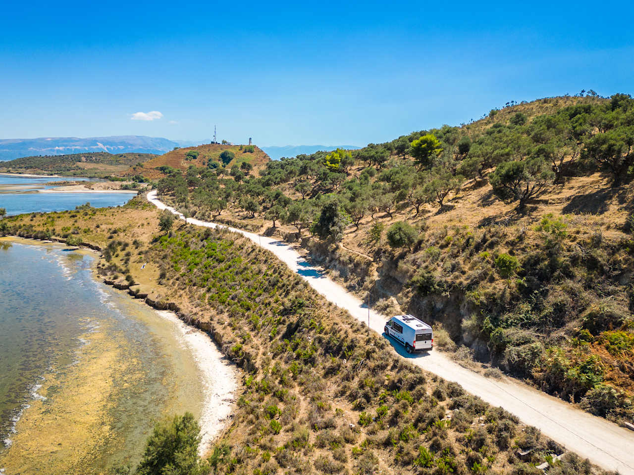 Campervan fährt auf einer Straße am Meer