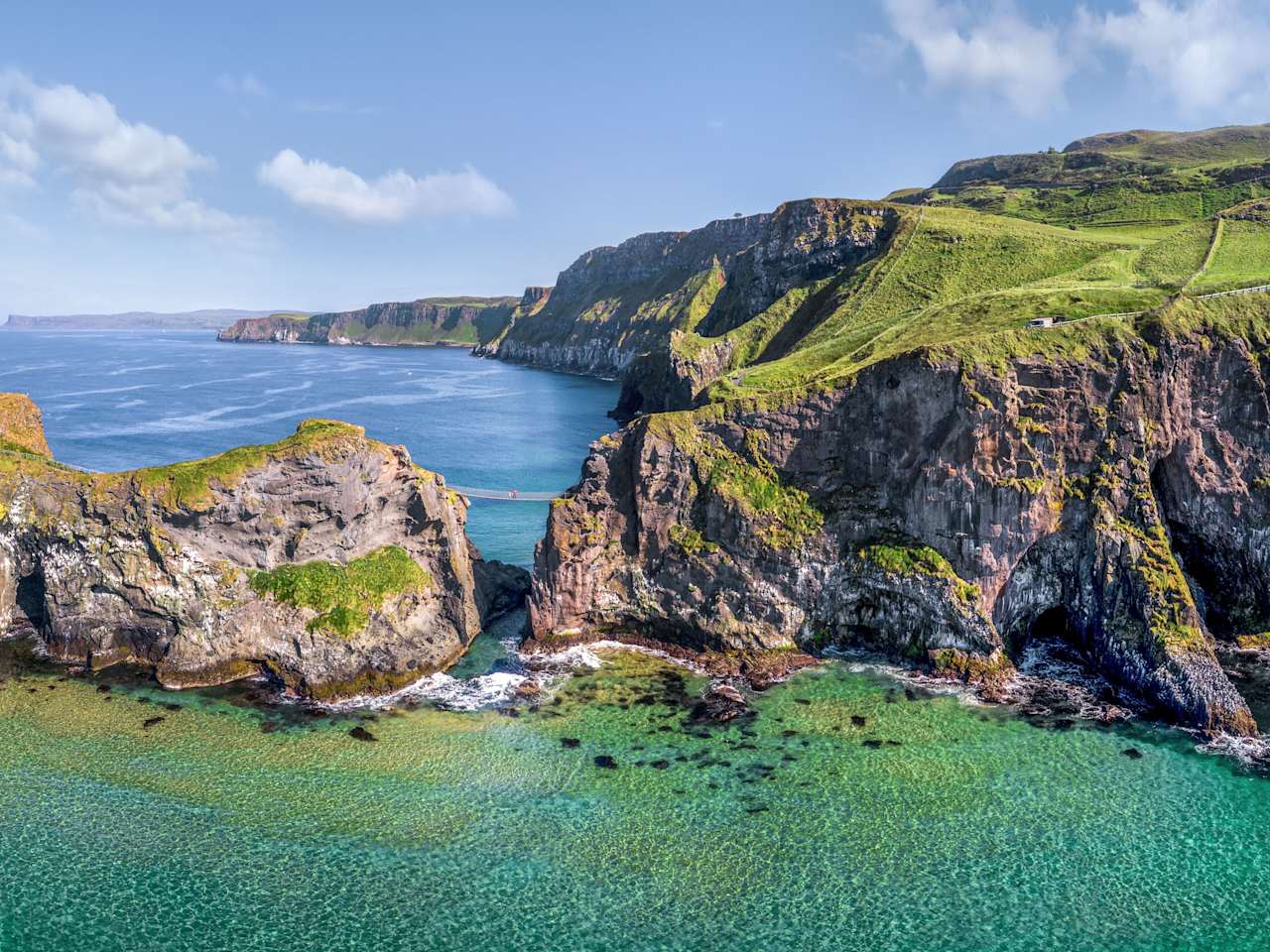 Eine Hängebrücke verbindet eine felsige Insel mit dem Festland.