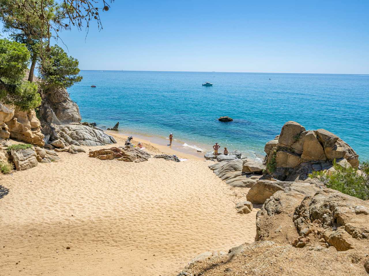 Menschen entspannen an einem Strand zwischen Felsen.