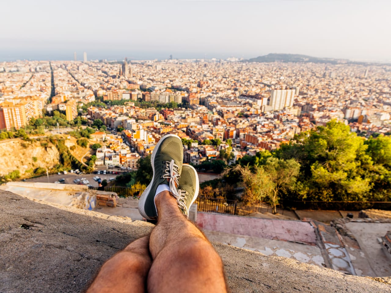 Ein Mann sitzt auf einer Mauer und schaut auf Barcelona.