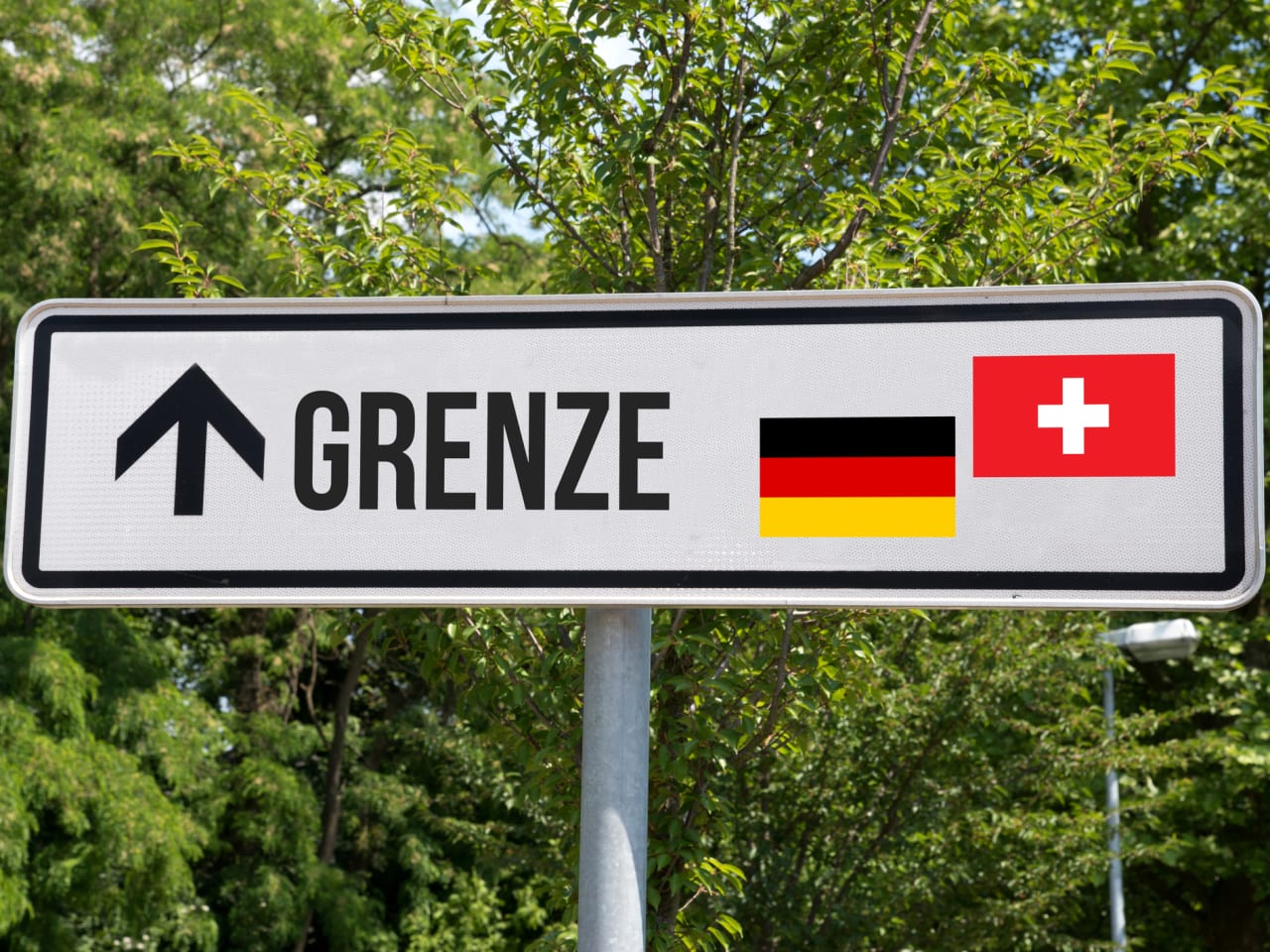 Ein Schild, welches zur Grenze zwischen Deutschland und der Schweiz zeigt. © Stadtratte/iStock / Getty Images Plus via Getty Images