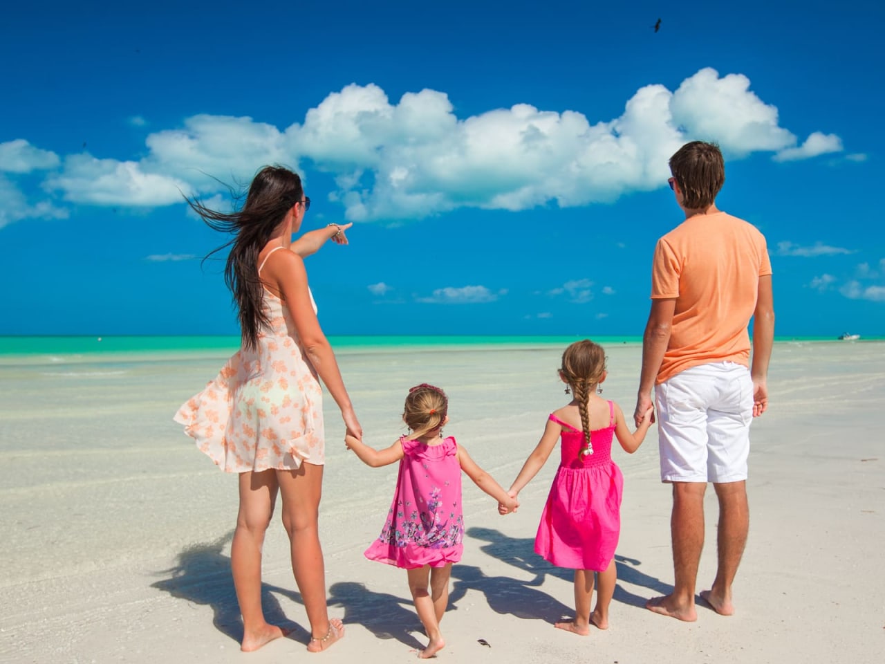 Eine Familie steht an einem Strand und blickt auf das Meer.
