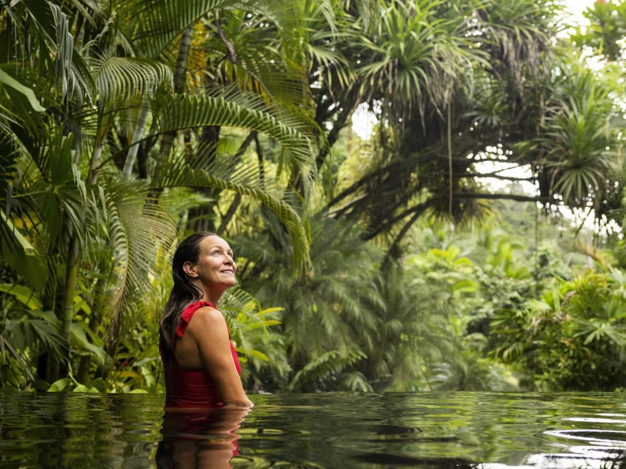 Eine Frau lächelt in einem Pool im Dschungel von Costa Rica.