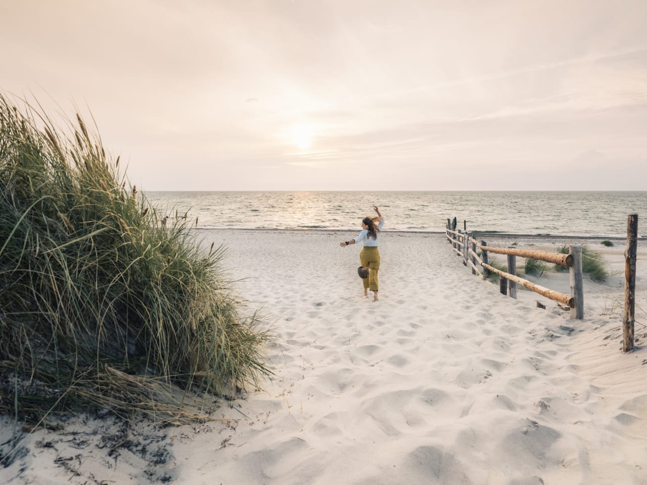 Eine Frau rennt einen Strand in Mecklenburg-Vorpommern, Deutschland, entlang. © Francesco Vaninetti Photo/Moment via Getty Images