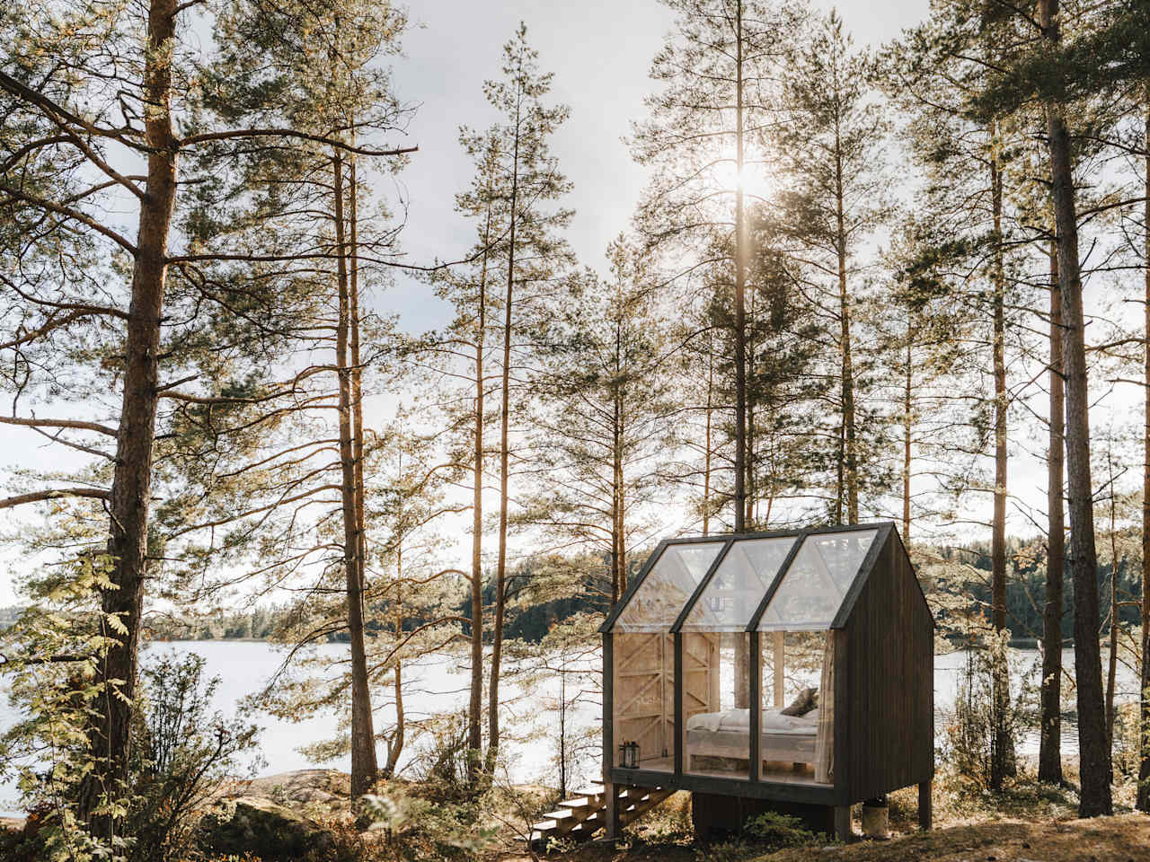 Eine Hütte mit Glaswänden in einem Wald am See, Schweden, Skandinavien.