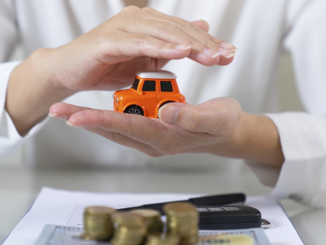 Eine Frau hält ein Spielzeugauto in den Händen, im Vordergrund liegt Geld.