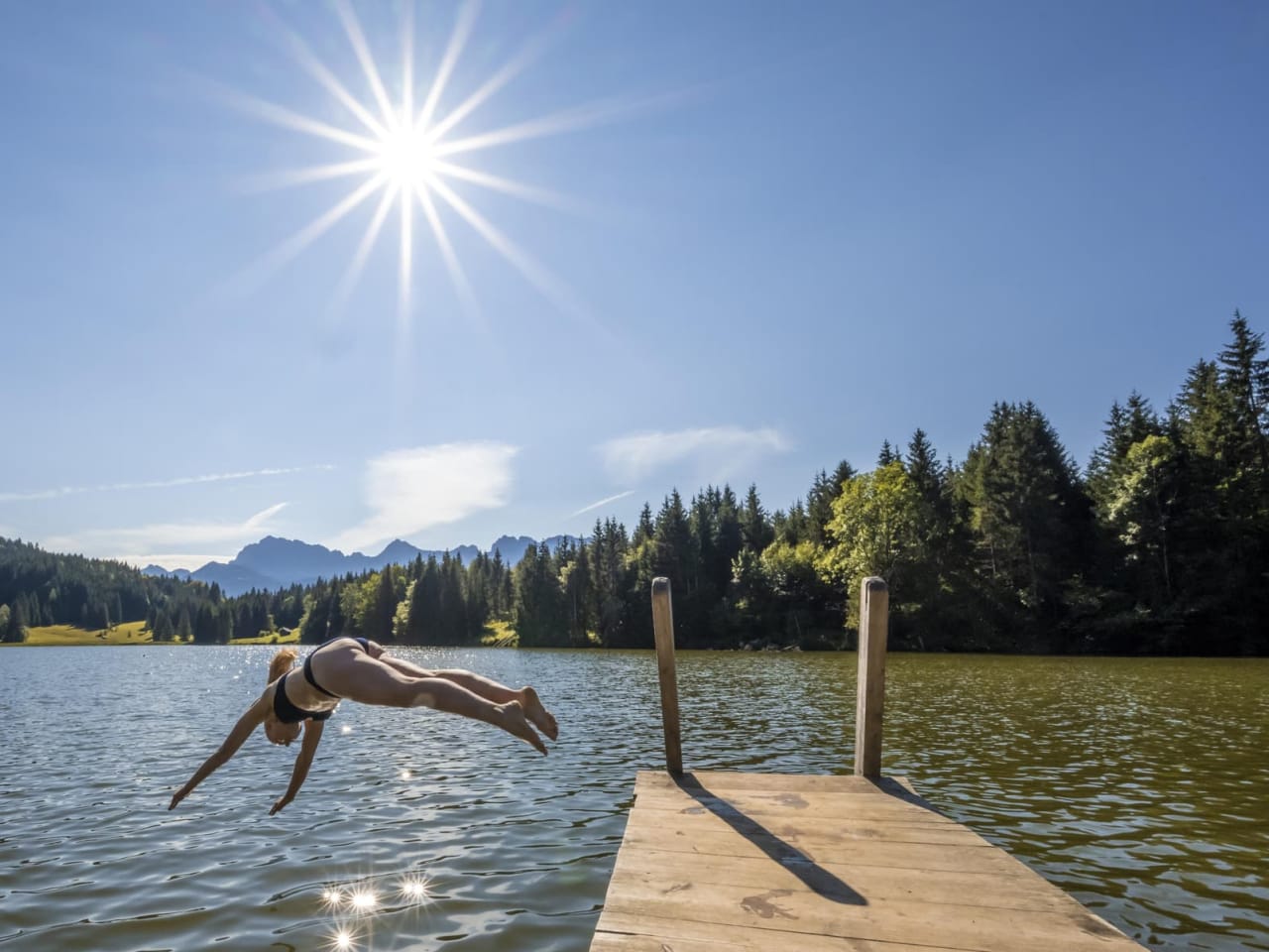 Eine Frau macht einen Kopfsprung in den See, Bayern, Deutschland.