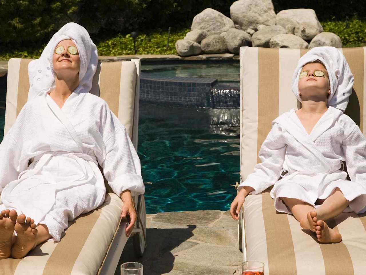 Frau und Kind entspannen mit einer Gurkenmaske im Gesicht am Pool.