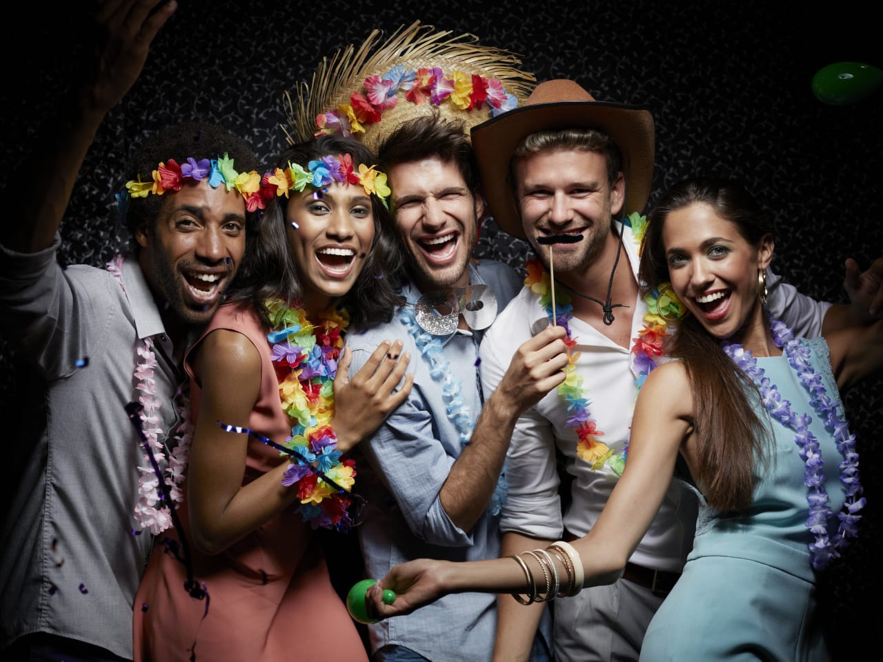 Lachende Freunde tragen Girlanden in einem Nachtclub. © Morsa Images/DigitalVision via Getty Images