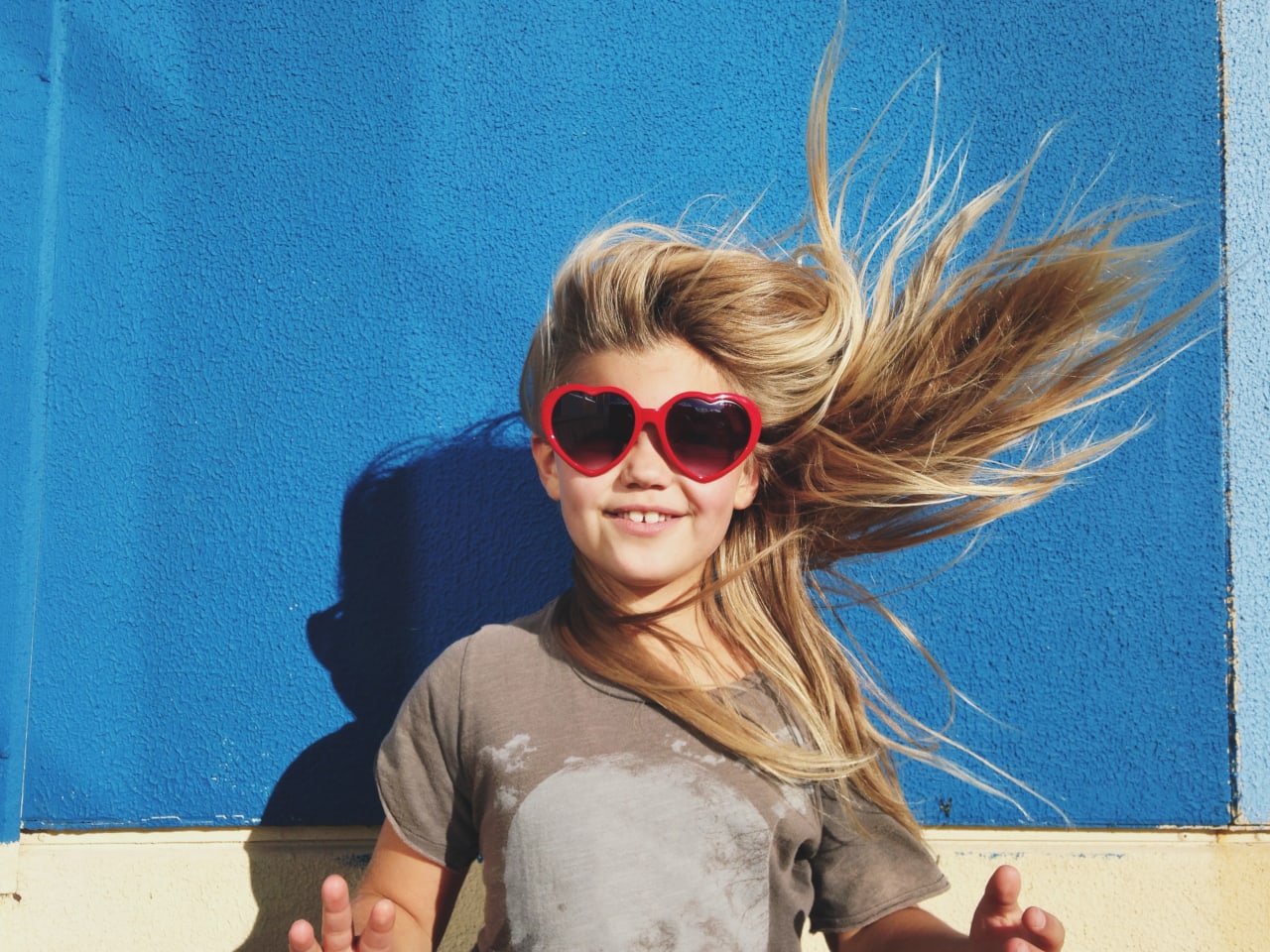 Glückliches Mädchen mit Herzen-Sonnenbrille. © Jodie Griggs/The Image Bank via Getty Images