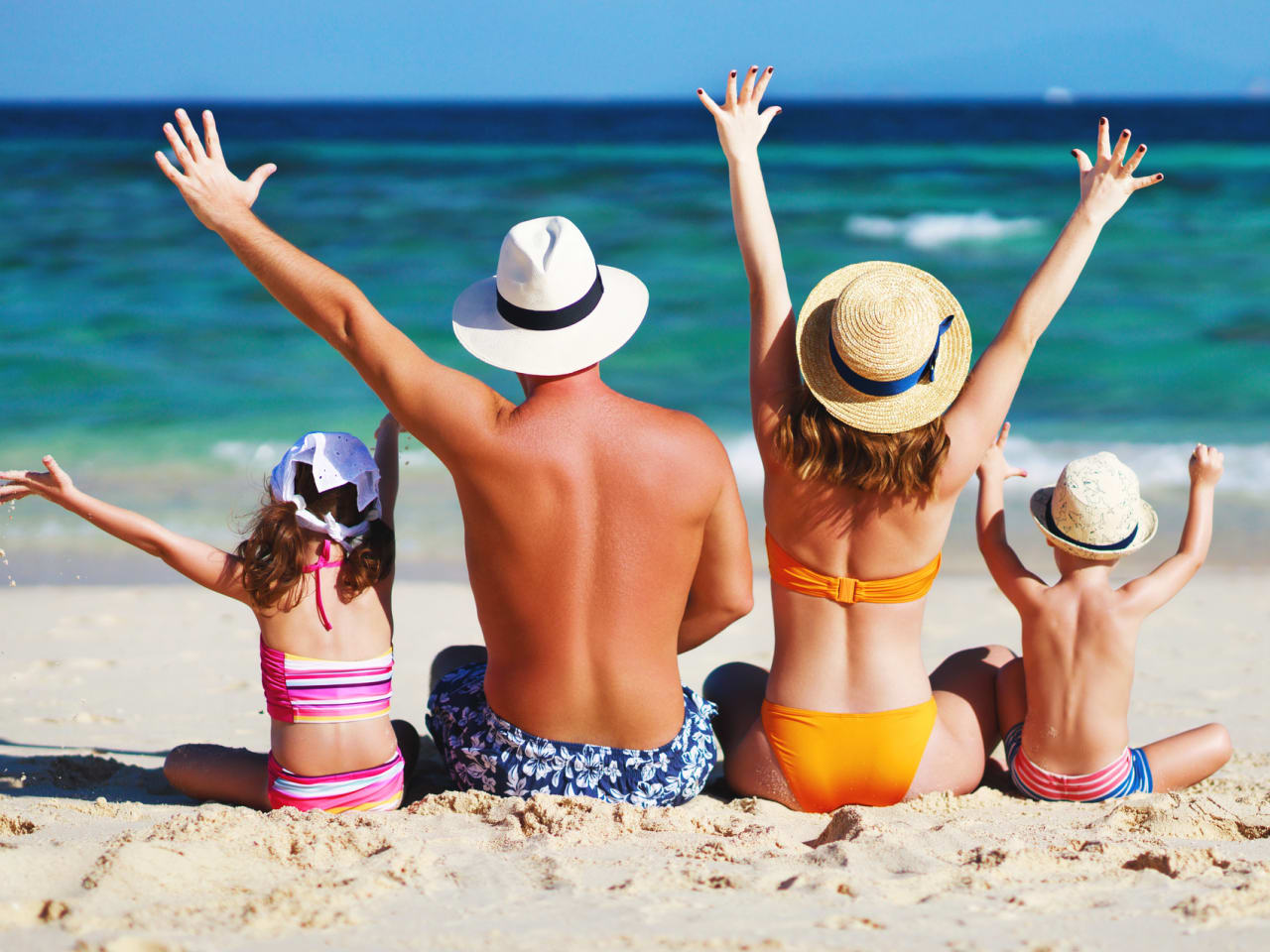 glückliche Familie mit Vater Mutter und Kindern sitzen am Strand © iStock.com/evgenyatamanenko