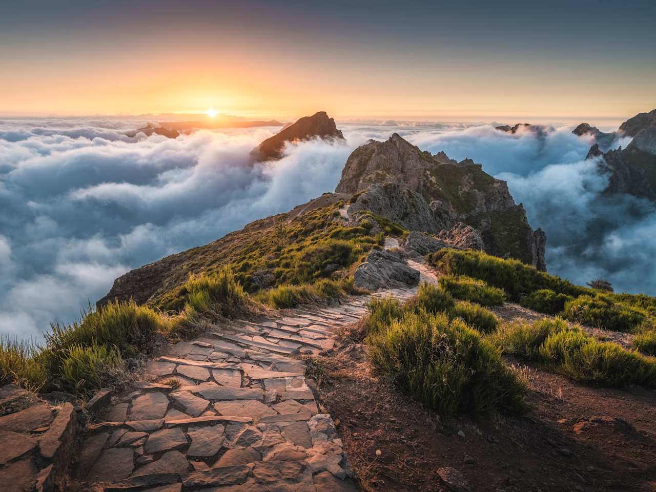 Gepflasterter Fußweg am Pico do Arieiro über den Wolken zum Sonnenaufgang, Madeira. © Marco Bottigelli via Getty Images