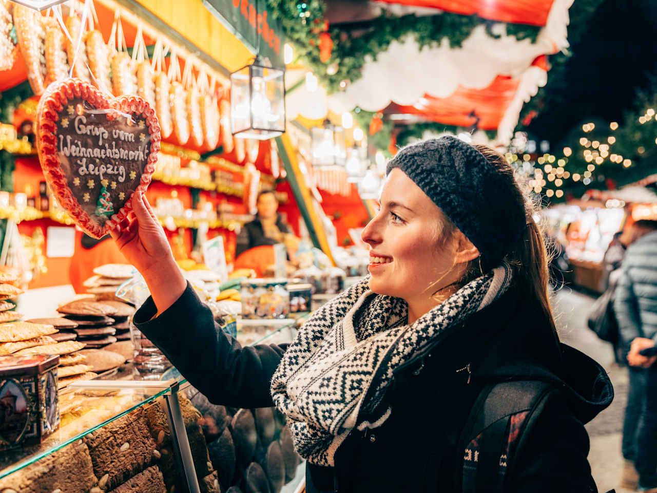 Eine Frau lächelt ein Lebkuchenherz an.
