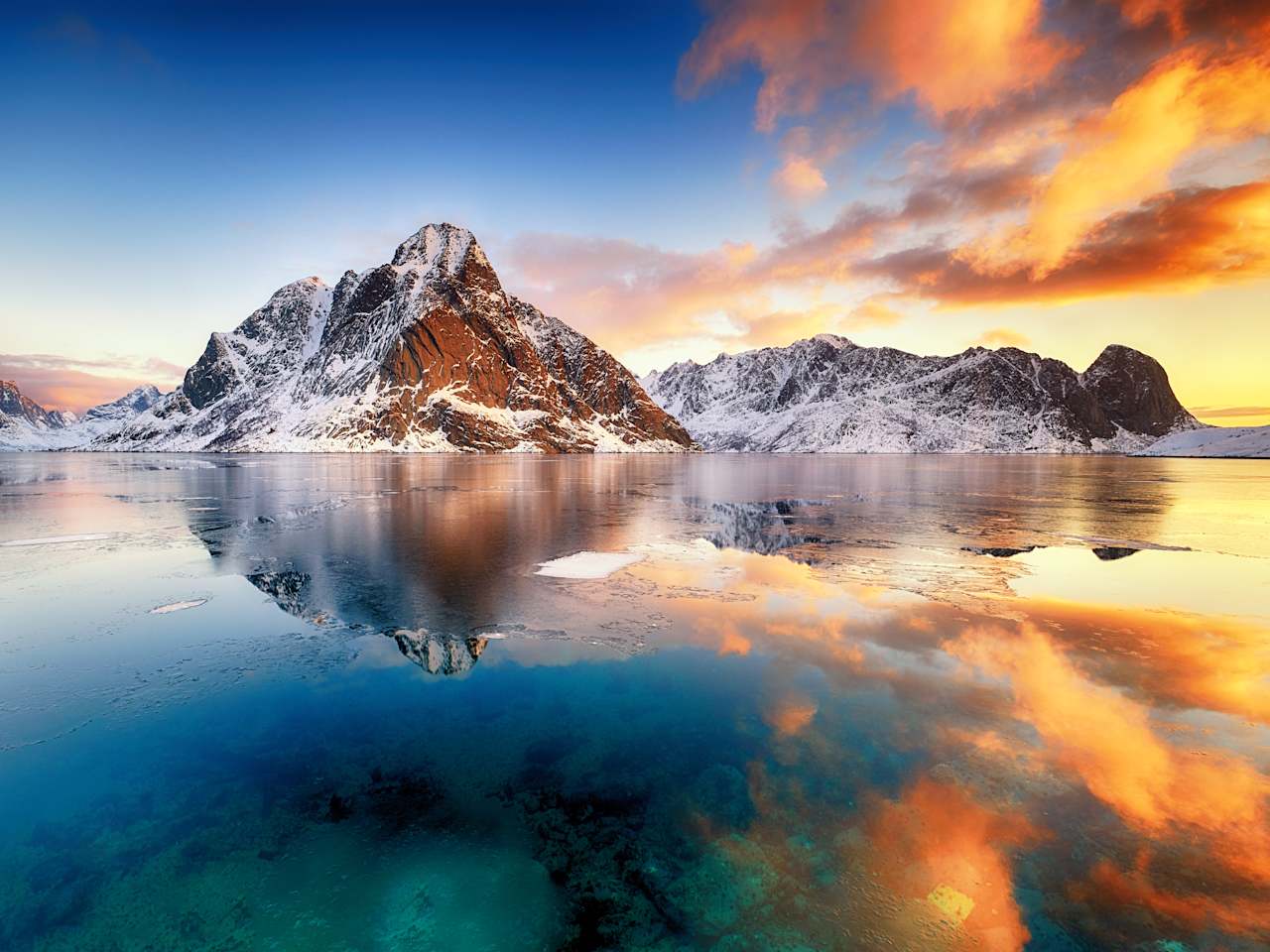 Schneebedeckte Berge spiegeln sich im Eiswasser.