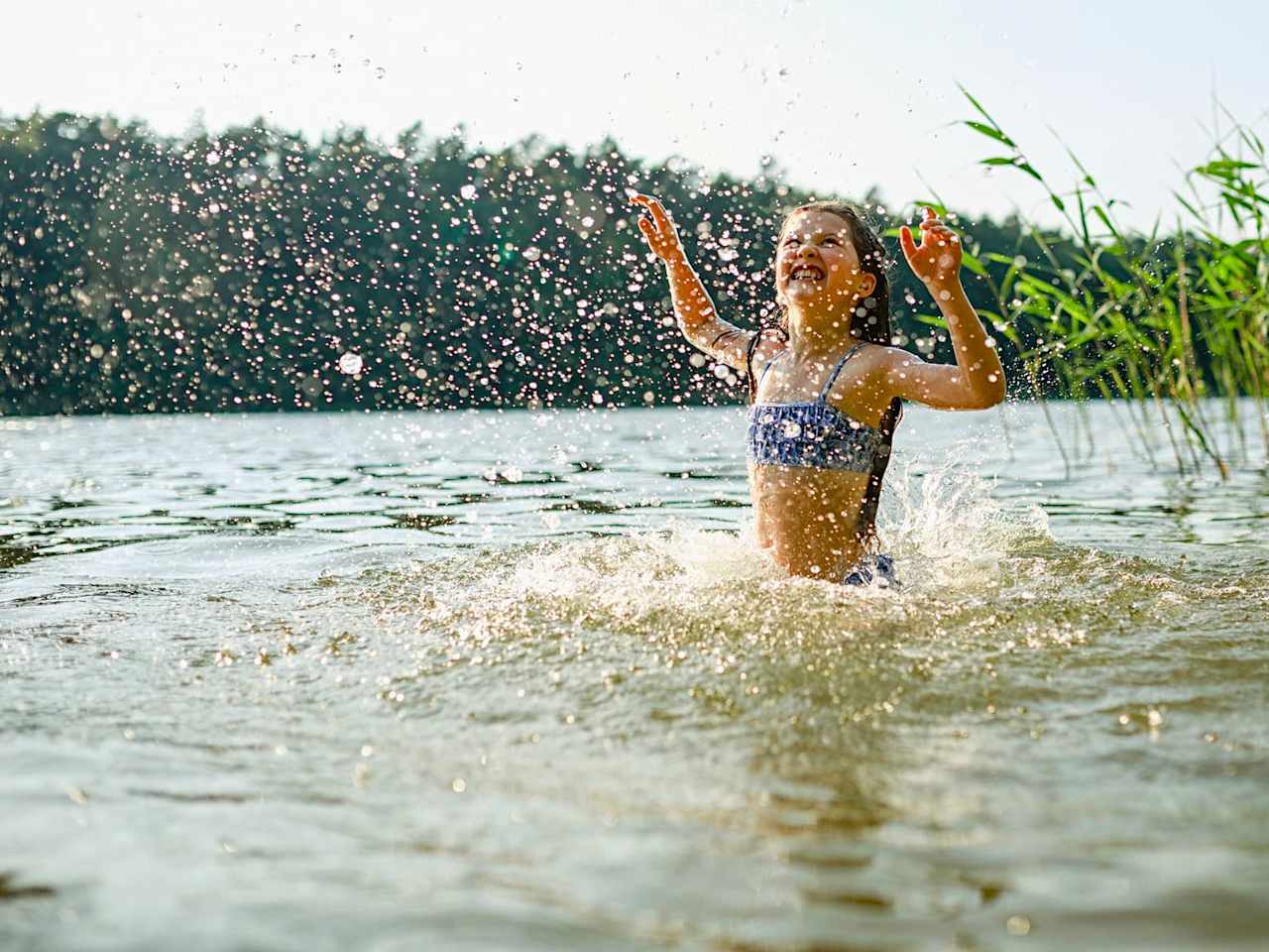 Ein Mädchen planscht im Wasser.