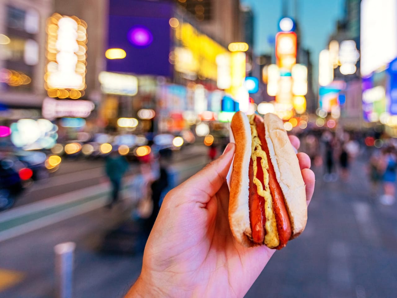 Ein Mann isst ein Hot Dog am Times Square in New York.
